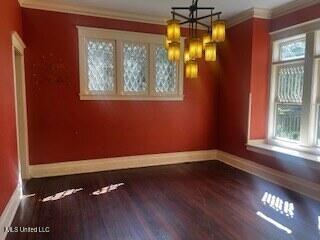 56 John St, Clarksdale, MS 38614 - unfurnished dining area featuring baseboards, healthy amount of natural light, wood finished floors, crown molding, and a chandelier