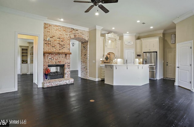 unfurnished living room featuring dark wood-type flooring, a brick fireplace, ceiling fan, and ornamental molding