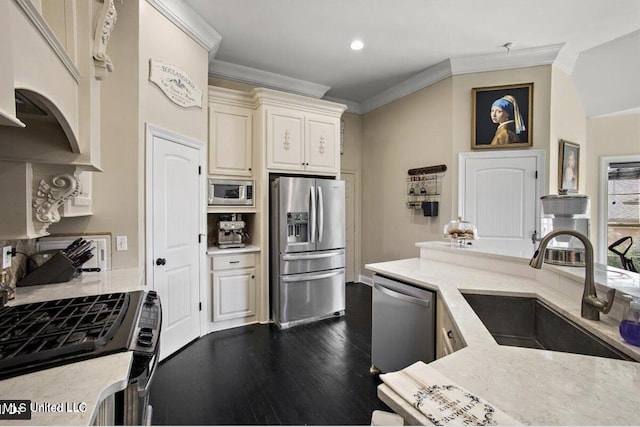 kitchen featuring appliances with stainless steel finishes, crown molding, sink, cream cabinets, and hardwood / wood-style flooring