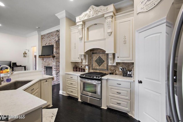 kitchen with backsplash, sink, appliances with stainless steel finishes, cream cabinetry, and dark hardwood / wood-style flooring