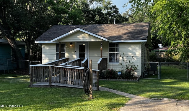 view of front of house with covered porch, a shingled roof, a front yard, and fence
