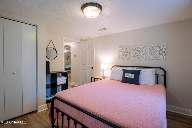 bedroom featuring a closet, a textured ceiling, and dark hardwood / wood-style flooring