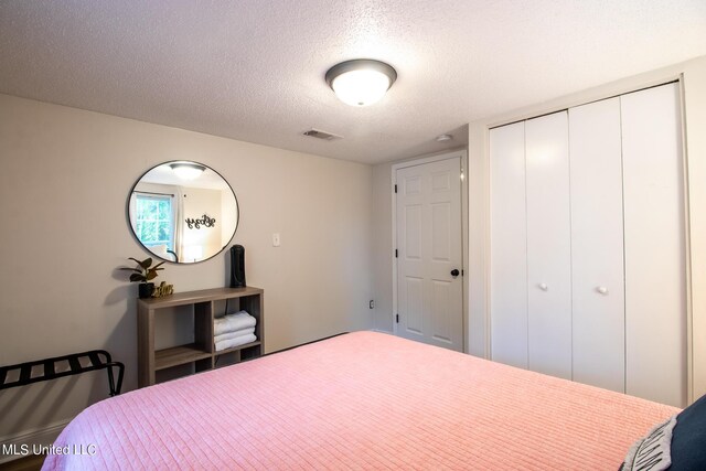 bedroom featuring visible vents, a textured ceiling, and a closet