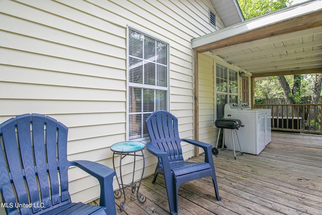 wooden terrace featuring washing machine and clothes dryer and fence