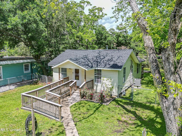 view of front of property featuring a fenced backyard, a front lawn, cooling unit, a porch, and roof with shingles