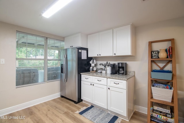kitchen featuring baseboards, light wood-style flooring, white cabinetry, and stainless steel fridge