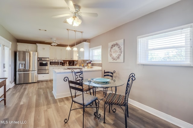 dining room featuring a ceiling fan, baseboards, and light wood-style flooring
