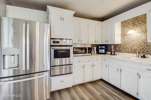 kitchen featuring a sink, a warming drawer, stainless steel appliances, and tile countertops