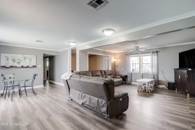 living area featuring baseboards, visible vents, crown molding, and wood finished floors