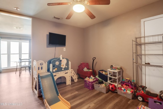recreation room featuring visible vents, a ceiling fan, and wood finished floors