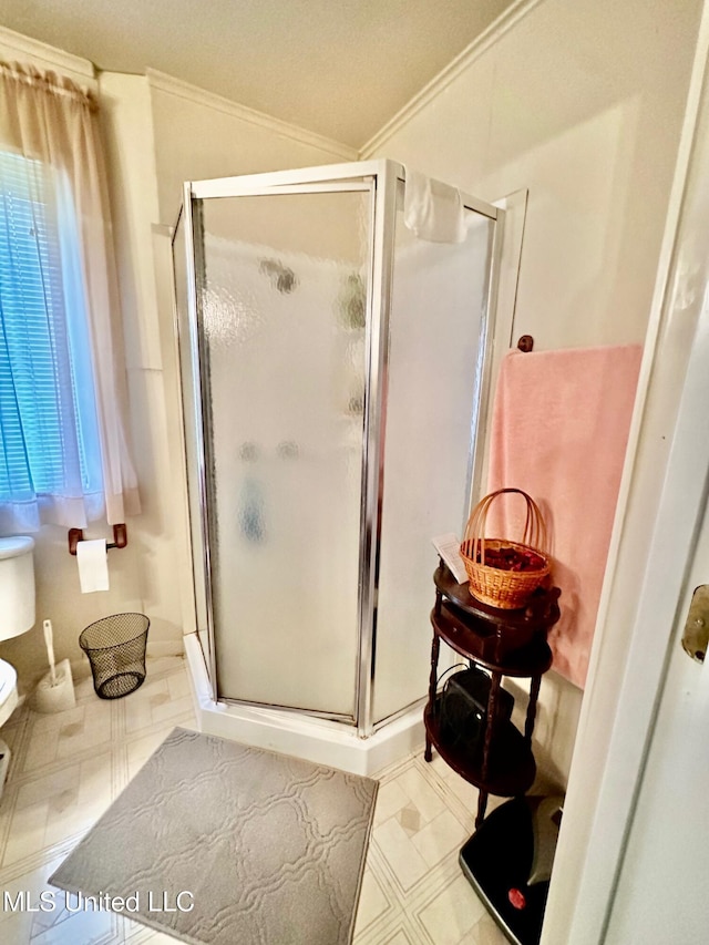 bathroom with a shower with door, toilet, a wealth of natural light, and crown molding