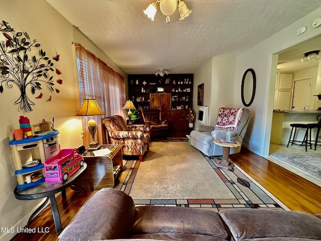 living room featuring ceiling fan, wood-type flooring, and a textured ceiling