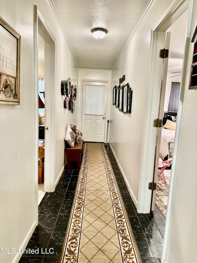 hallway featuring a textured ceiling and crown molding