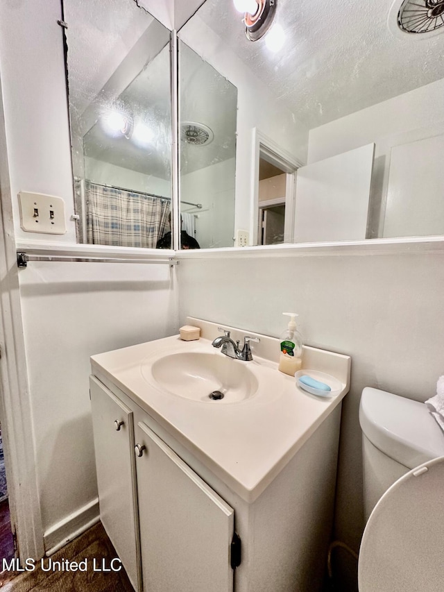 bathroom featuring vanity, a textured ceiling, and toilet