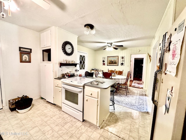 kitchen featuring a breakfast bar, a textured ceiling, white range with electric stovetop, ceiling fan, and white cabinetry