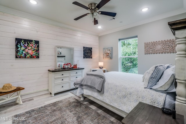 bedroom featuring light hardwood / wood-style floors, wooden walls, and ceiling fan