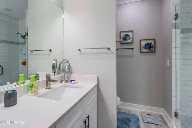 bathroom featuring vanity, toilet, walk in shower, and wood-type flooring