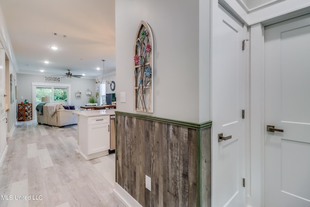 hallway featuring ornamental molding, light hardwood / wood-style flooring, and a chandelier