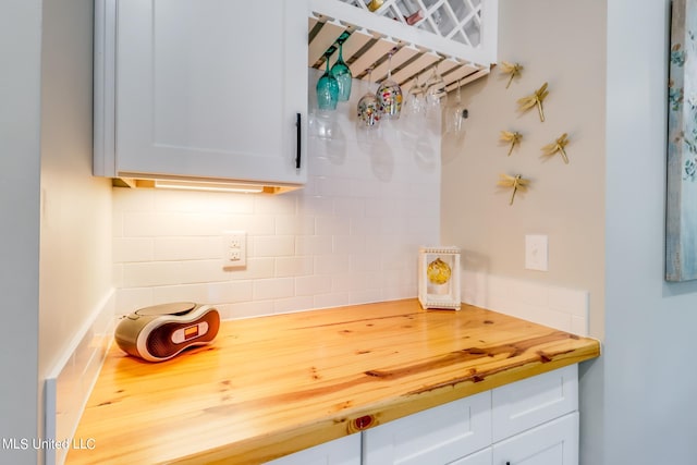 kitchen featuring butcher block counters, backsplash, and white cabinets