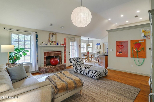 living room featuring wood-type flooring, vaulted ceiling, and a fireplace