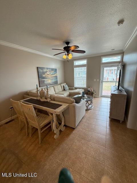 living area featuring a textured ceiling, ceiling fan, light tile patterned floors, baseboards, and crown molding