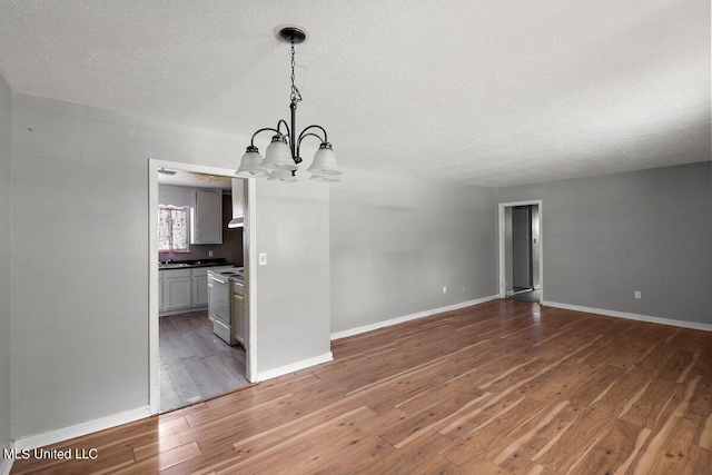 unfurnished dining area with a notable chandelier, a textured ceiling, and dark hardwood / wood-style flooring