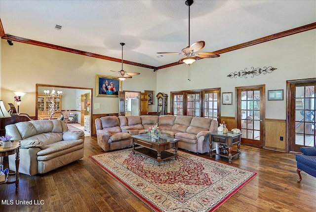 living room with crown molding, dark hardwood / wood-style floors, ceiling fan with notable chandelier, and wood walls