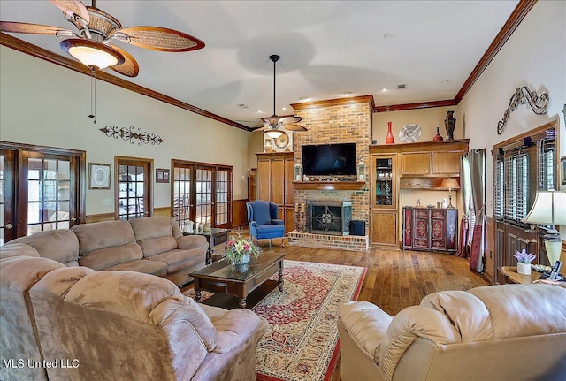 living room featuring ceiling fan, a brick fireplace, light hardwood / wood-style floors, crown molding, and french doors