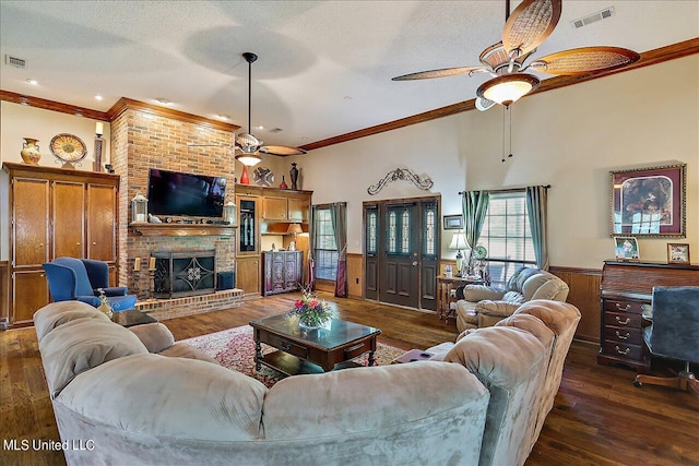 living room featuring dark hardwood / wood-style flooring, a brick fireplace, ornamental molding, and ceiling fan