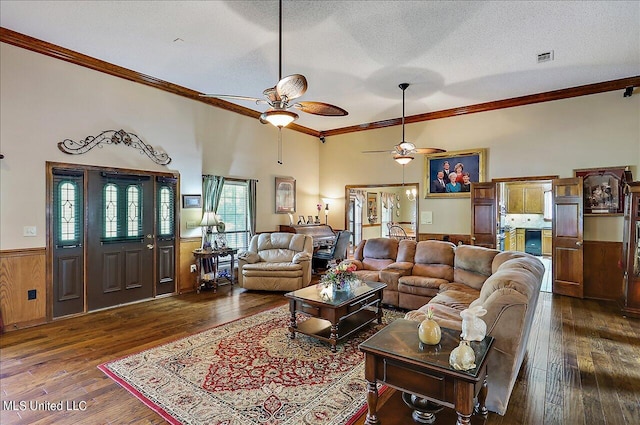 living room featuring ceiling fan, a textured ceiling, ornamental molding, dark wood-type flooring, and wooden walls