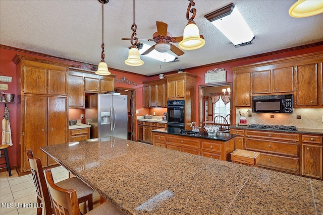 kitchen featuring a breakfast bar, ornamental molding, black appliances, and a textured ceiling