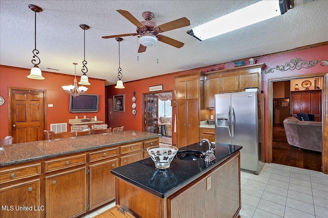 kitchen with a kitchen island, a textured ceiling, ceiling fan with notable chandelier, stainless steel refrigerator with ice dispenser, and decorative light fixtures