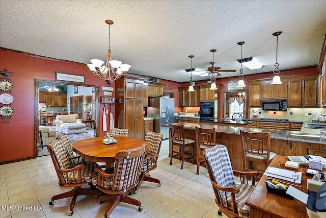 tiled dining space featuring ornamental molding, a textured ceiling, and ceiling fan with notable chandelier