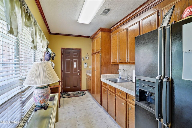 kitchen featuring black refrigerator with ice dispenser, sink, crown molding, light tile patterned floors, and a textured ceiling