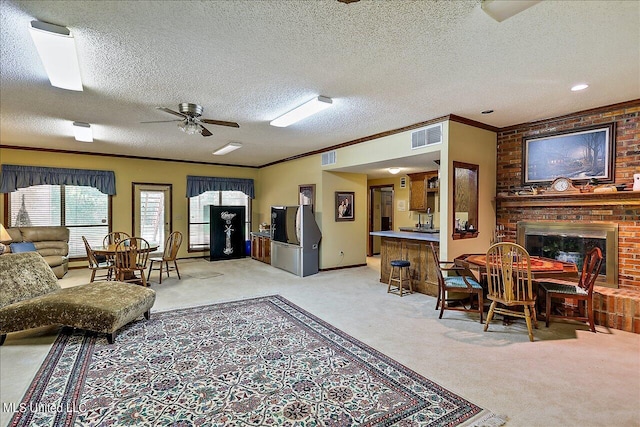 carpeted living room featuring crown molding, a textured ceiling, a brick fireplace, and ceiling fan