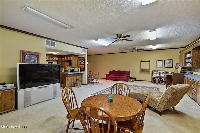 dining space featuring light carpet, ornamental molding, a textured ceiling, and ceiling fan