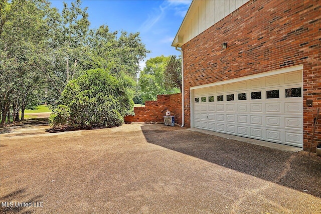 1600 Pine Hill Dr, Raymond, MS 39154 - view of home's exterior featuring asphalt driveway, brick siding, a garage, and board and batten siding