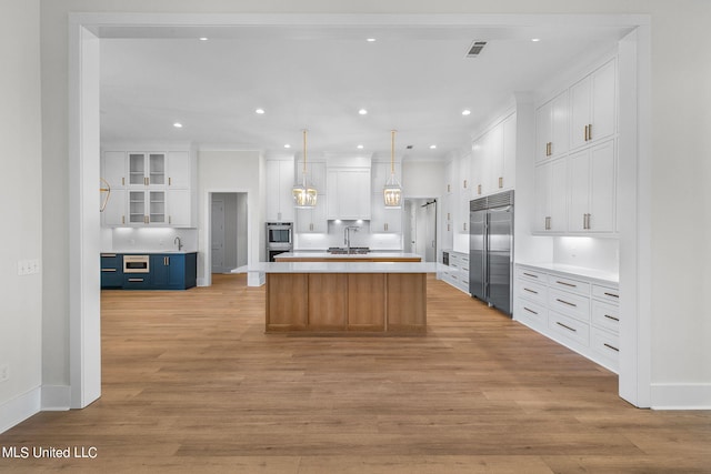 54 Windermere Blvd, Madison, MS 39110 - kitchen featuring appliances with stainless steel finishes, white cabinets, light countertops, light wood-style flooring, and a center island with sink