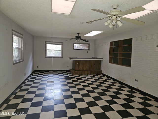 spare room with ceiling fan, brick wall, and a textured ceiling