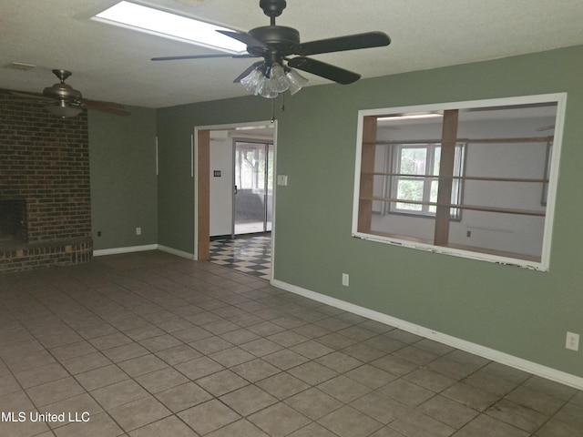 unfurnished living room with ceiling fan, tile patterned floors, and a fireplace