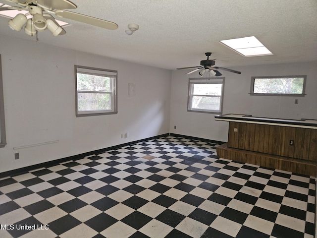 spare room with ceiling fan, a wealth of natural light, a textured ceiling, and a skylight