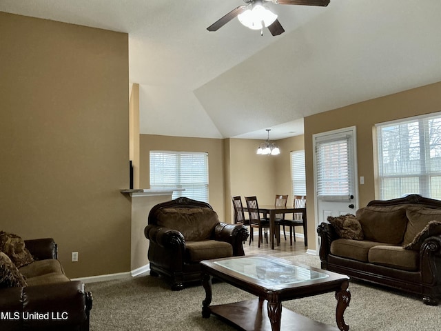 carpeted living room featuring ceiling fan with notable chandelier and vaulted ceiling