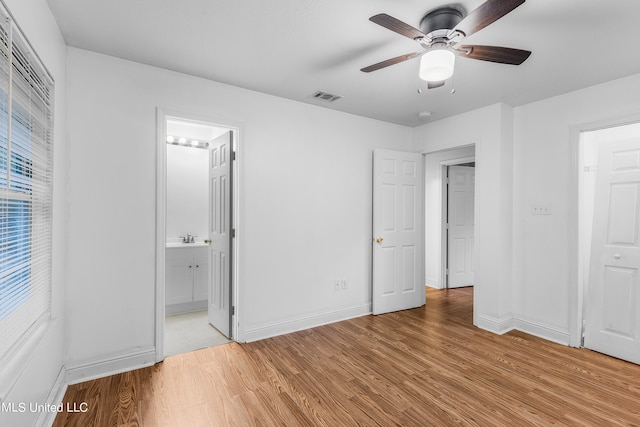 unfurnished bedroom featuring sink, light hardwood / wood-style flooring, ensuite bathroom, and ceiling fan