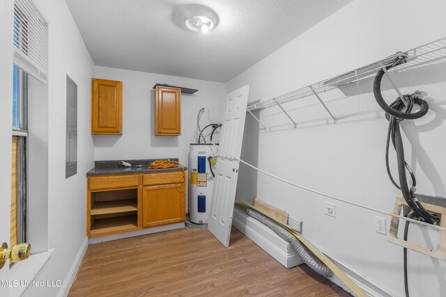 interior space with electric water heater, a textured ceiling, and light hardwood / wood-style floors