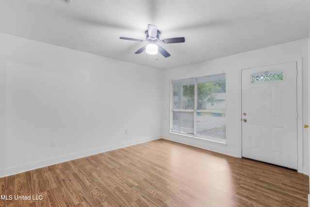 foyer with ceiling fan, a textured ceiling, and hardwood / wood-style floors