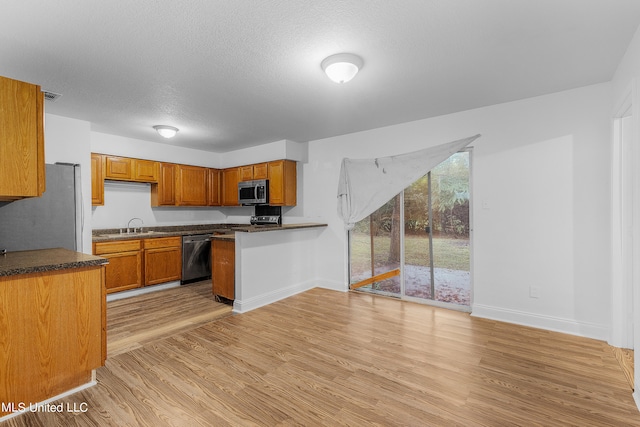 kitchen featuring stainless steel appliances, a textured ceiling, sink, and light wood-type flooring