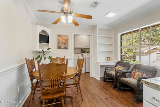 dining room with independent washer and dryer, built in features, light hardwood / wood-style floors, ceiling fan, and ornamental molding