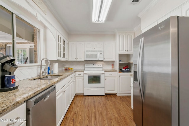 kitchen with appliances with stainless steel finishes, sink, backsplash, white cabinets, and ornamental molding