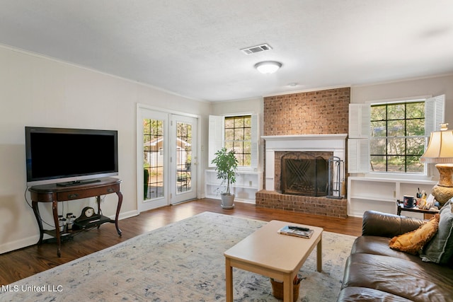 living room featuring ornamental molding, dark wood-type flooring, and a brick fireplace