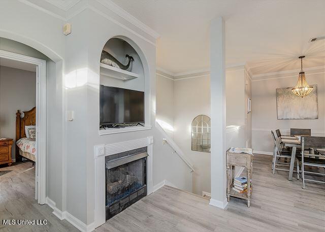 living room featuring built in shelves, crown molding, and hardwood / wood-style floors